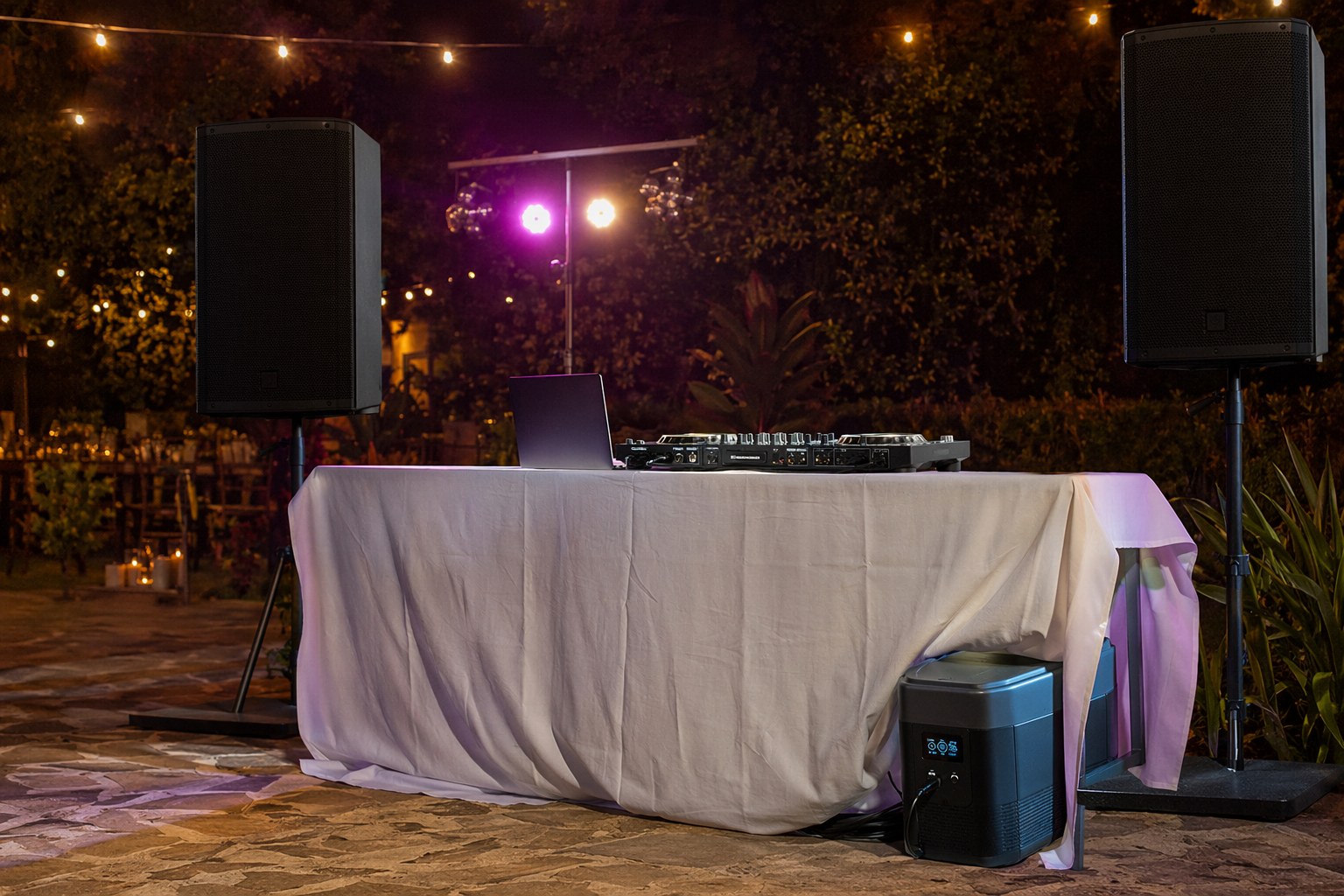 Event sound system and lighting rig powered by a battery station behind a draped table